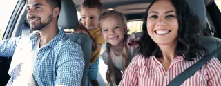 משפחה מחייכת ברכב שכור ב-Kaizen Rent